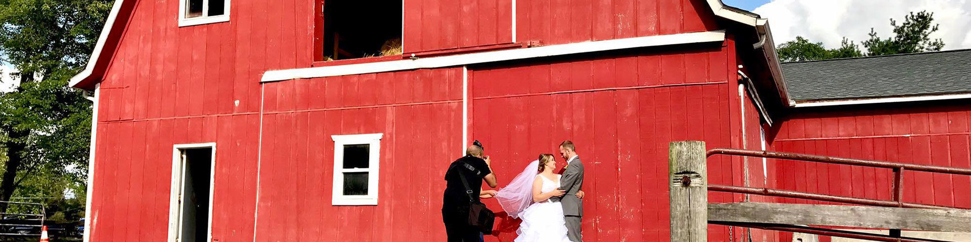 bride and groom posing for photos in front of a barn